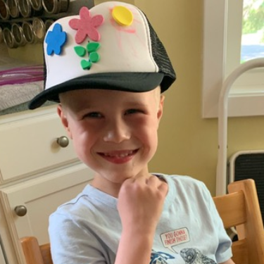 Boy smiling wearing hat decorated with flower stickers